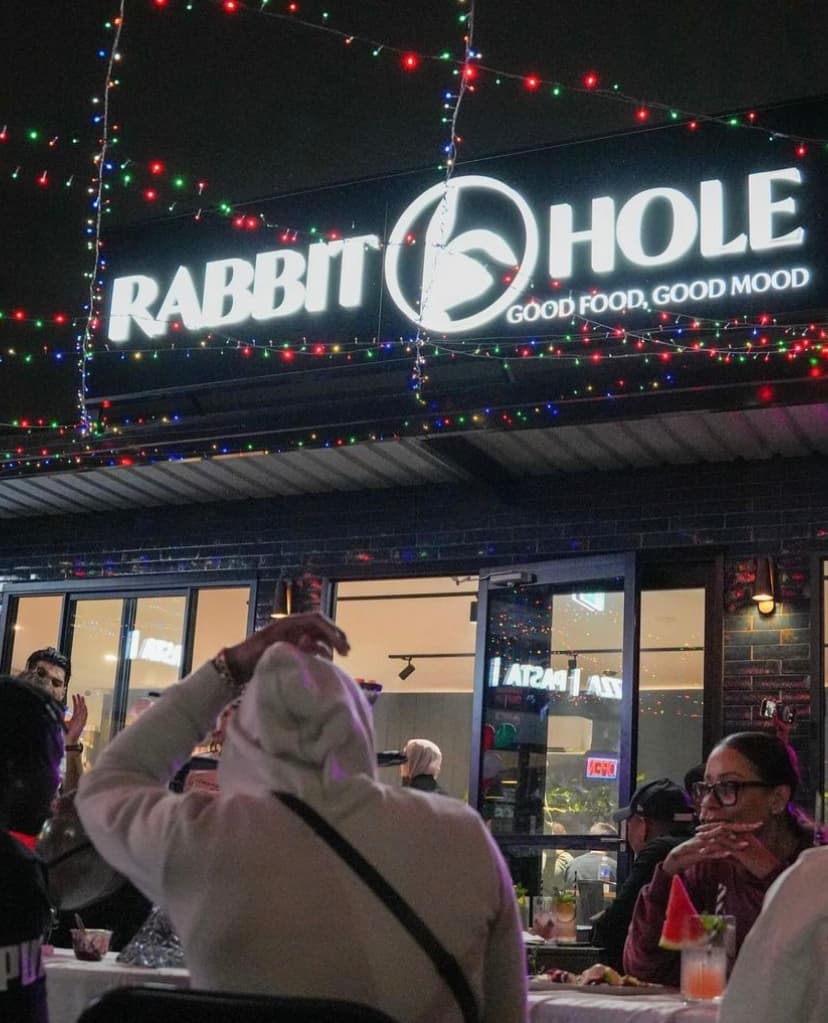 Rabbit Hole - Outdoor storefront sign reading 'Good Food, Good Mood' under festive string lights in Roselands